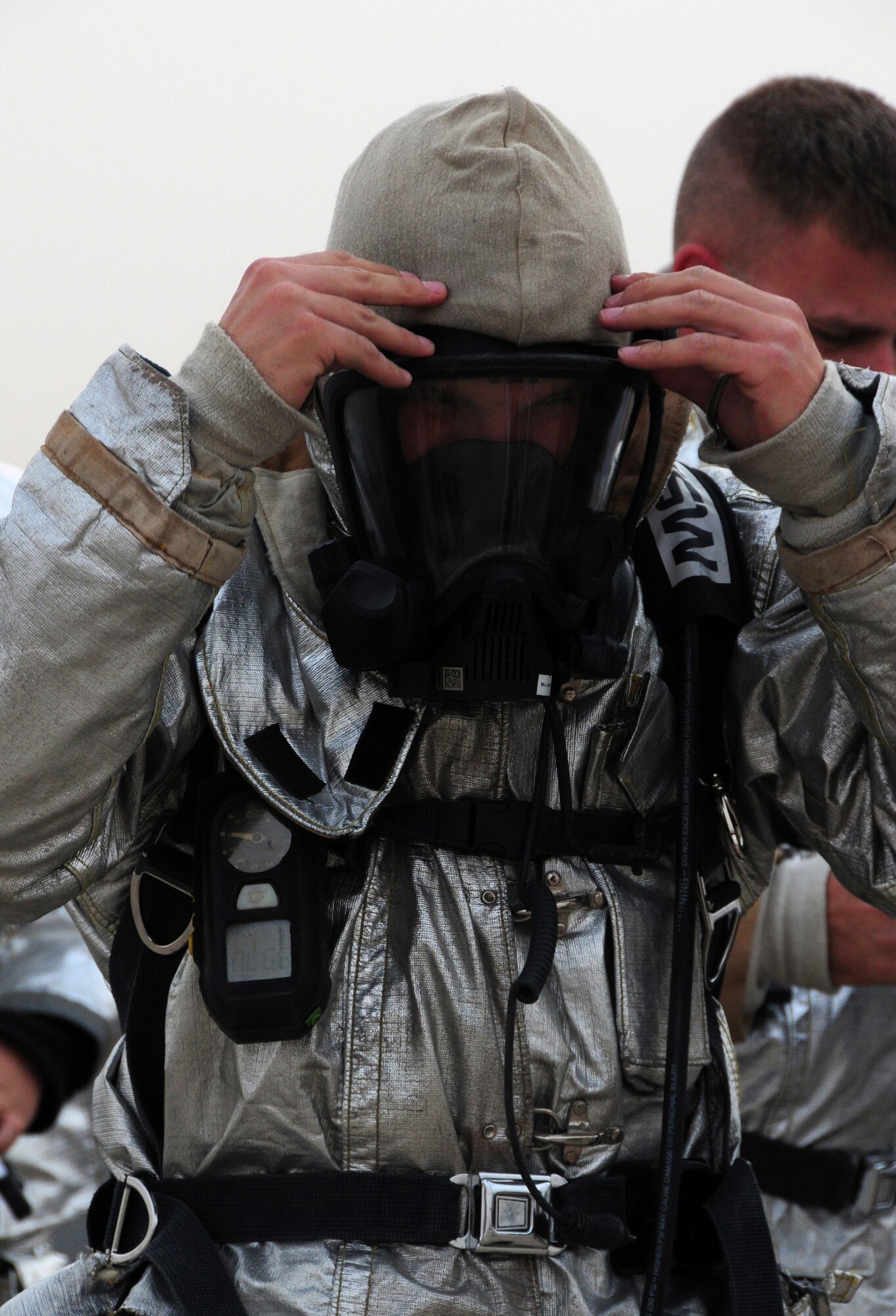 U.S. Air Force Master Sgt. Jake Blair, 386th Expeditionary Civil Engineer Squadron Fire Department assistant chief of operations, tightens the straps on his oxygen mask in preparation for live fire training at a nearby base in Southwest Asia April 29, 2010. Live fire training is an annual requirement for all U.S. Air Force firefighters. (U.S. Air Force photo by Staff Sgt. Lakisha A. Croley/Released)