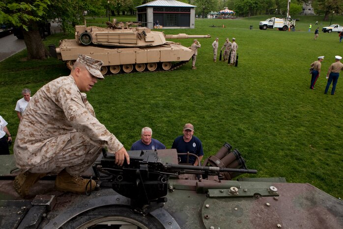 Cpl. Brendan Faul, a Marine with Echo Company, 4th Tank Battalion, who's a native of Noblesville, Ind., shows a couple of Bostonian firefighters the mounted M2 .50 caliber machine gun on an M1A1 Abrams Main Battle Tanks May 3 at Boston Common. This exhibition was during the first day of Marine Week Boston, which honors and recognizes the contributions of Marines, including Boston-based hometown heroes and their families.