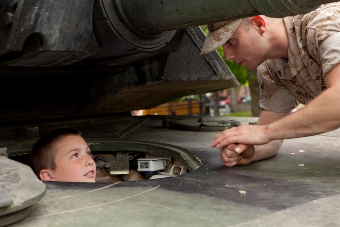 A Marine tank crewman with Echo Company, 4th Tank Battalion, shows a young Bostonian what it's like to be in the driver seat of an M1A1 Abrams Main Battle Tank during an exhibition of Marine gear, weapons and vehicles May 3 at Boston Common. The exhibition was during the first day of Marine Week Boston, which honors and recognizes the contributions of Marines, including Boston-based hometown heroes and their families.