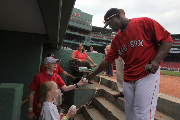 A Boston Red Sox player autographs a baseball for Jake and Shaelin Murphy, the son and daughter of Maj. Neil Murphy of New York City Public Affairs just before they stepped up to their job as honorary bat boy and bat girl May 3, 2010.