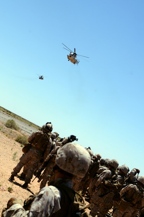 Marines with 1st Battalion, 1st Marine Regiment, watch CH-53 Super Stallions land at Auxiliary Airfield 2, prior to beginning a helicopter-borne raid on a simulated insurgent camp in the Chocolate Mountains in California, May 3, 2010. Inserting in four different locations, via MV-22 Ospreys, CH-46 Sea Knights and CH-53 Super Stallions, Companies B and C, along with the Weapons Company, assaulted the camp with small-arms fire and rockets. Here supporting the current Weapons and Tactics Instructor course, the Camp Pendleton, Calif.-based unit is also training for a deployment early next year with the 13th Marine Expeditionary Unit.