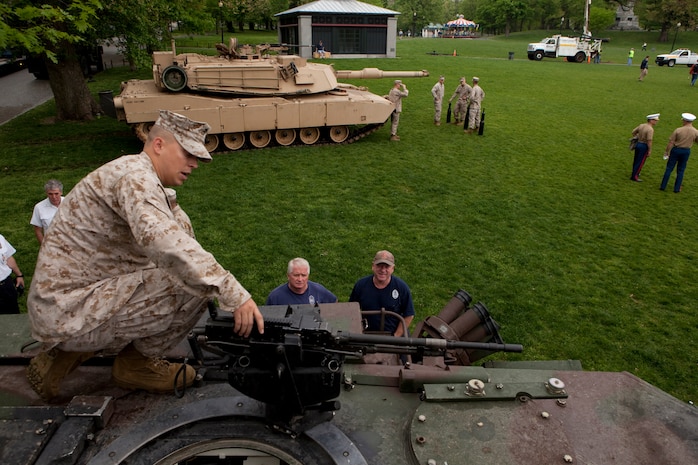 Cpl. Brendan Faul, a Marine with Echo Company, 4th Tank Battalion, who's a native of Noblesville, Ind., shows a couple of Bostonian firefighters the mounted M2 .50 caliber machine gun on an M1A1 Abrams Main Battle Tanks May 3 at Boston Common. This exhibition was during the first day of Marine Week Boston, which honors and recognizes the contributions of Marines, including Boston-based hometown heroes and their families.