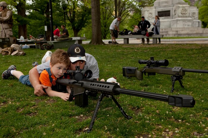 Nicholas Martin, a 4-year-old from Medford, Mass., and his uncle Robert Parks, lays down behind the scope of a M82 .50 caliber Special Application Scoped Rifle during an exhibition of weapons used by Marines at Boston Common May 3. The exhibition was during the first day of Marine Week Boston, which honors and recognizes the contributions of Marines, including Boston-based hometown heroes and their families.