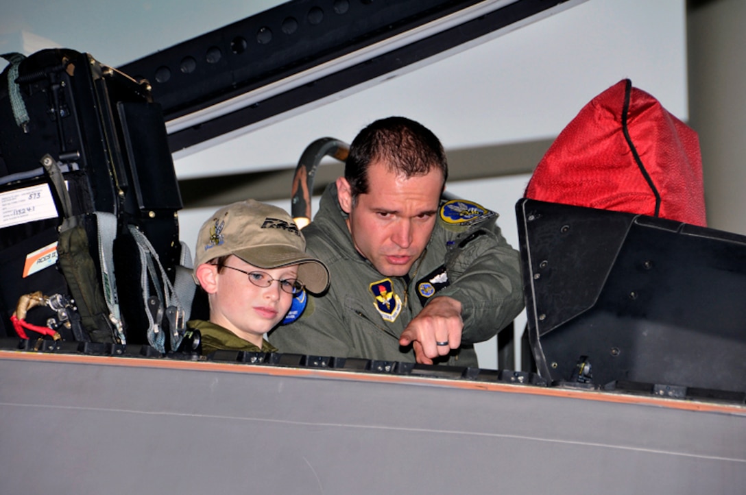 Capt. Michael “Slim” Palik, 43rd Fighter Squadron instructor pilot, points out the F-22’s cockpit technology to Jordan “Rocket” Shuman during his “Pilot for a Day” visit to Tyndall AFB, Fla., April 30, 2010.