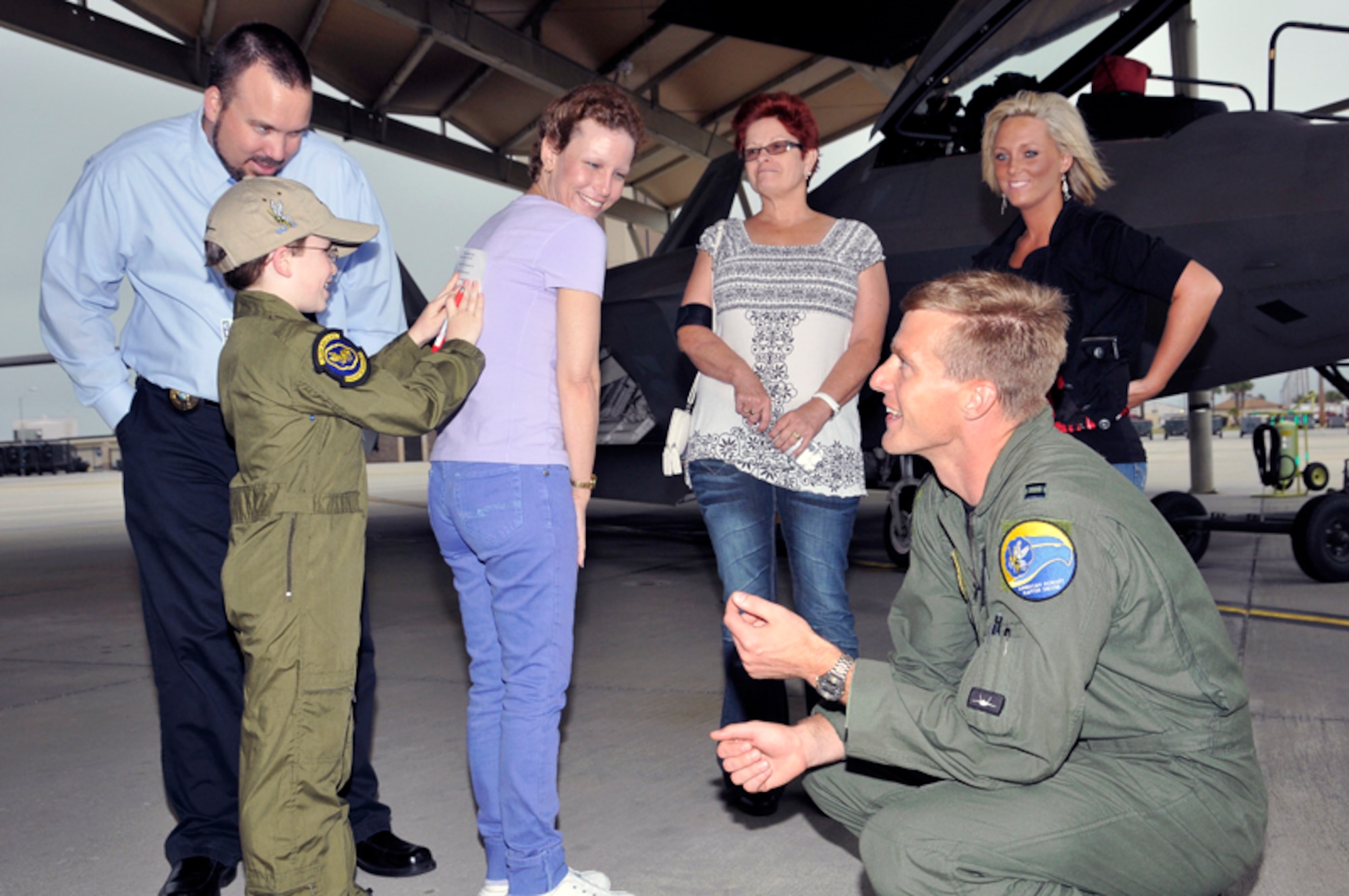 Jordan “Rocket” Shuman gets some help from his mom, Tanya (center) and Capt. Scott “Omar” Bradley (kneeling), as he completes his ‘flightline certification test’ while his father Chris, grandmother, Brenda, and step sister, Ashley look on.