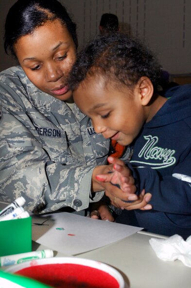 MINOT AIR FORCE BASE, N.D. – Senior Airman Takiyah Anderson, 5th Communications Squadron client systems personnel, finger paints with her son, Jailen, during the Kid’s Block Party at the David C. Jones Youth Center here April 30. The Block Party included games, gifts, crafts and other activities for children of military members. (U.S. Air Force photo by Senior Airman Jesse Lopez)