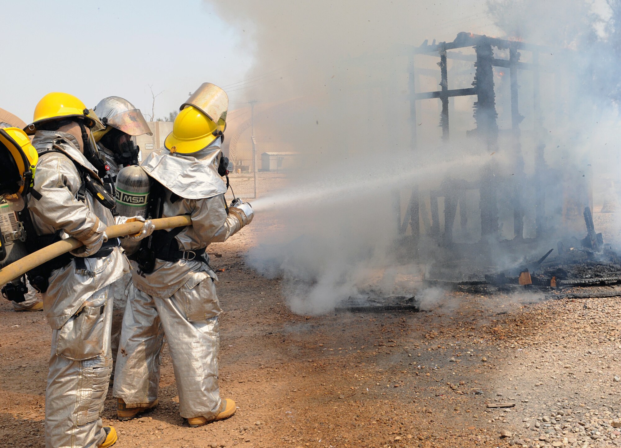 Firefighters with the 332nd Civil Engineer Squadron, stand by and aid Iraqi firefighters as they put out a fire at Joint Base Balad, Iraq, April 30, 2010. Seven volunteer firefighters from Bakir Village have trained with the JBB firefighters over several weeks. The training started with learning basic skills and has progressed to the last stage, fighting a fire. (U.S. Air Force photo by Master Sgt. Linda C. Miller/Released)