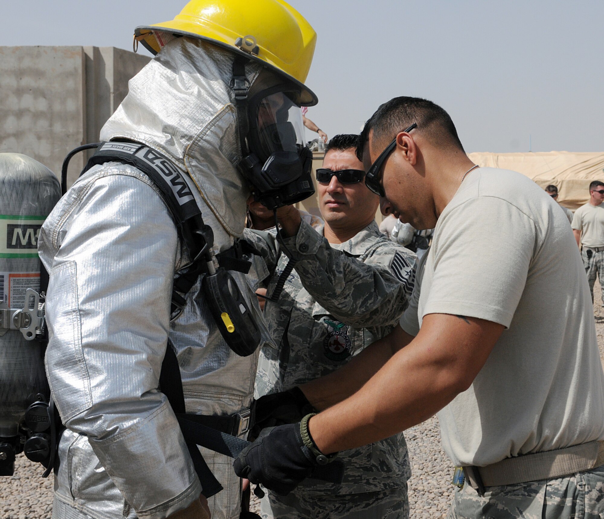 Firefighter Staff Sgt. Stephen Sanabria (right) and Tech. Sgt. Stephen Perez, assistant chief of fire prevention, both members with the 332nd Civil Engineer Squadron, help an Iraqi firefighter don his personal protective equipment prior to fighting a fire at Joint Base Balad, Iraq, April 30, 2010. Seven volunteer firefighters from Bakir Village have trained with the JBB firefighters over several weeks. The training started with learning basic skills and has progressed to the last stage, fighting a fire. (U.S. Air Force photo by Master Sgt. Linda C. Miller/Released)