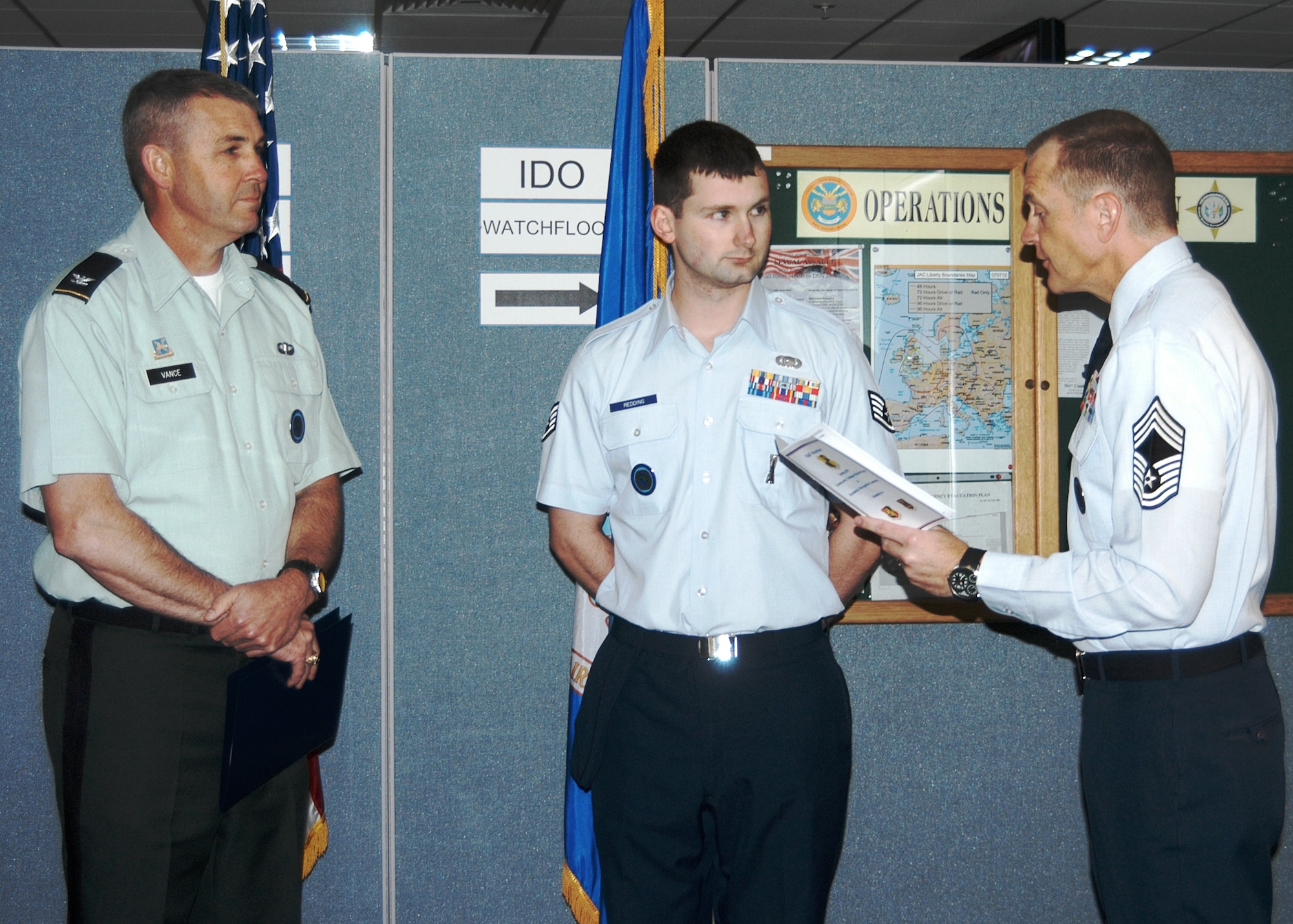 One of the Intelligence and Knowledge Development Directorate-Molesworth (IKD-M) leaders, United States Army Colonel Michael D. Vance (left) watches as United States Air Force Chief Master Sgt. Scott W. Lumpkin (right), Senior Enlisted Leader for IKD-M, explains the Air Force Association’s 2010 William H. Pitsenbarger Award won by United States Air Force Staff Sgt. Ian M.G. Redding (center). (Photo by Melony Angelilli)