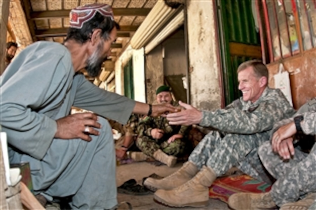 An Afghan man offers a cup of tea to U.S. Army Gen. Stanley A. McChrystal, commander of NATO's International Security Assistance Force and U.S. Forces in Afghanistan, during a meeting with village elders and Afghan National Army members in Adira, Afghanistan, April 28, 2010.