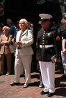 Cpl. Henry E. Figueroa, a color guardsman with Logistics Supplies Division, Marine Corps Logistics Base, Ga., and native of Trent, N.J., stands at the position of attention while Albany Marine Band performs, ''Marines' Hymn,'' during a street performance in downtown Boston, Mass., in a crowd of surrounding Bostonians, May 4, 2010. Albany Marine Band performed several songs to include, ''Stars and Stripes, Marines' Hymn, What a Wonderful World and Semper Fi.'' The band's performance played a key role in Marine Week Boston to share the Corps' traditions, history and culture with Bostonians and help them learn about the Corps' value to the nation.