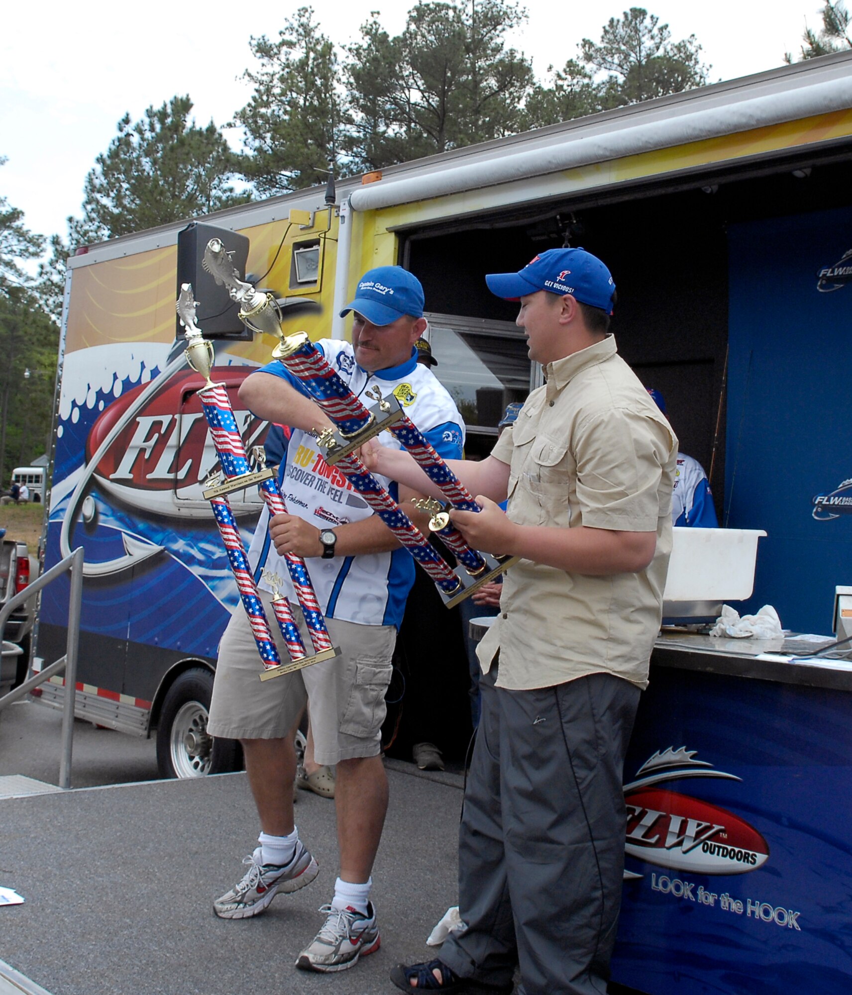 Tech. Sgt. James Poirrier (left), 43rd Logistics Readiness Squadron, and his co-angler, Army Staff Sgt. Parker Tootill, shake hands while holding their 1st place trophies during the closing ceremony of the fifth annual Warriors on the Water fishing tournament. The pair took 1st place with a combined weight of 21 pounds, three ounces. (U.S. Air Force photo/Senior Airman Kris Levasseur)