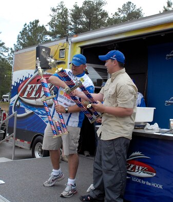 Tech. Sgt. James Poirrier (left), 43rd Logistics Readiness Squadron, and his co-angler, Army Staff Sgt. Parker Tootill, shake hands while holding their 1st place trophies during the closing ceremony of the fifth annual Warriors on the Water fishing tournament. The pair took 1st place with a combined weight of 21 pounds, three ounces. (U.S. Air Force photo/Senior Airman Kris Levasseur)