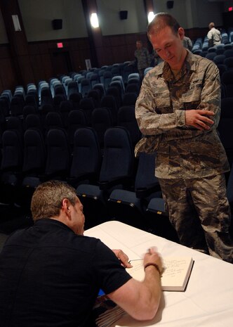 Senior Airman Richard Gilbert III waits as comedian Bernie McGrenahan signs his book following his comedy routine April 30, 2010, on Joint Base Charleston, S.C. Bernie McGrenahan tours around the United States speaking to America's youth about substance abuse, sexual assault and high-risk decisions with a 30-minute stand-up routine and 30-minute inspirational message. Airman Gilbert is a loadmaster with the 701st Airlift Squadron. (U.S. Air Force photo/Senior Airman Timothy Taylor)
