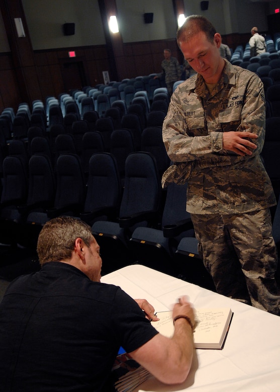 Senior Airman Richard Gilbert III waits as comedian Bernie McGrenahan signs his book following his comedy routine April 30, 2010, on Joint Base Charleston, S.C. Bernie McGrenahan tours around the United States speaking to America's youth about substance abuse, sexual assault and high-risk decisions with a 30-minute stand-up routine and 30-minute inspirational message. Airman Gilbert is a loadmaster with the 701st Airlift Squadron. (U.S. Air Force photo/Senior Airman Timothy Taylor)