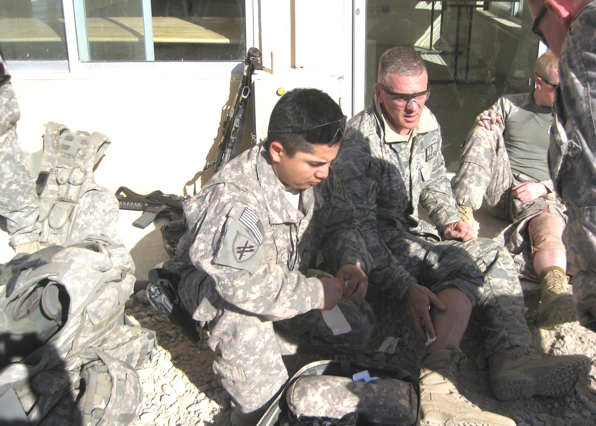 Sergeant Gestring, right, receives help for his wounded calf after ensuring all others wounded in the attack had been cared for.  He had provided care under fire “without regard to his own personnel safety and injuries he sustained from the blast.”  He triaged and treated nine other injured coalition forces and three Afghan National Police.  (Courtesy photo)