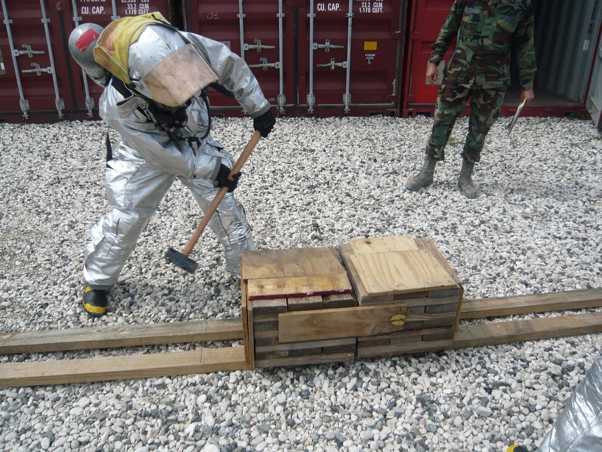 PORT-AU-PRINCE, Haiti -- Senior Airman Aaron Guillen, deployed from Beale Air Force Base, demonstrates how to complete the wood chop portion of the firefighter’s challenge course.  Firefighters had to use their imagination to build training aids that are normally purchased when at home station. Courtesy Photo 