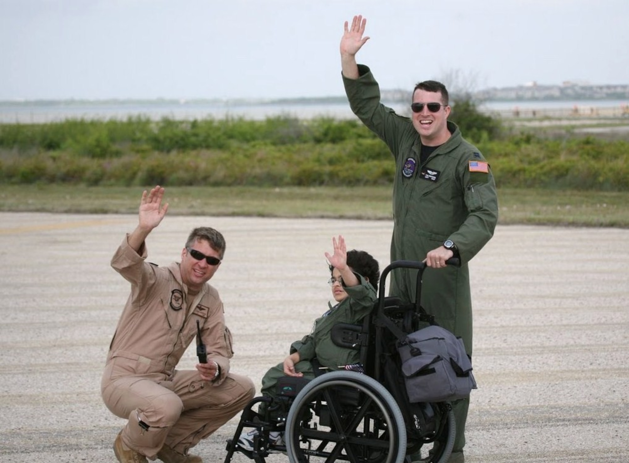NAVAL AIR STATION CORPUS CHRISTI, Texas -- Navy Lt. Josh Lostetter, Pilot-For-A-Day Eric Davis and Air Force Capt. Tim Robinson wave at a passing B-52 from the 2d Bomb Wing’s 20th Bomb Squadron as it flies over the runway. When scheduling allows, the 2d Bomb Wing uses the missions to practice off-station low approaches while at the same time providing support for the Pilot-For-A-Day program. (U.S. Coast Guard photo by Charles Dekle)