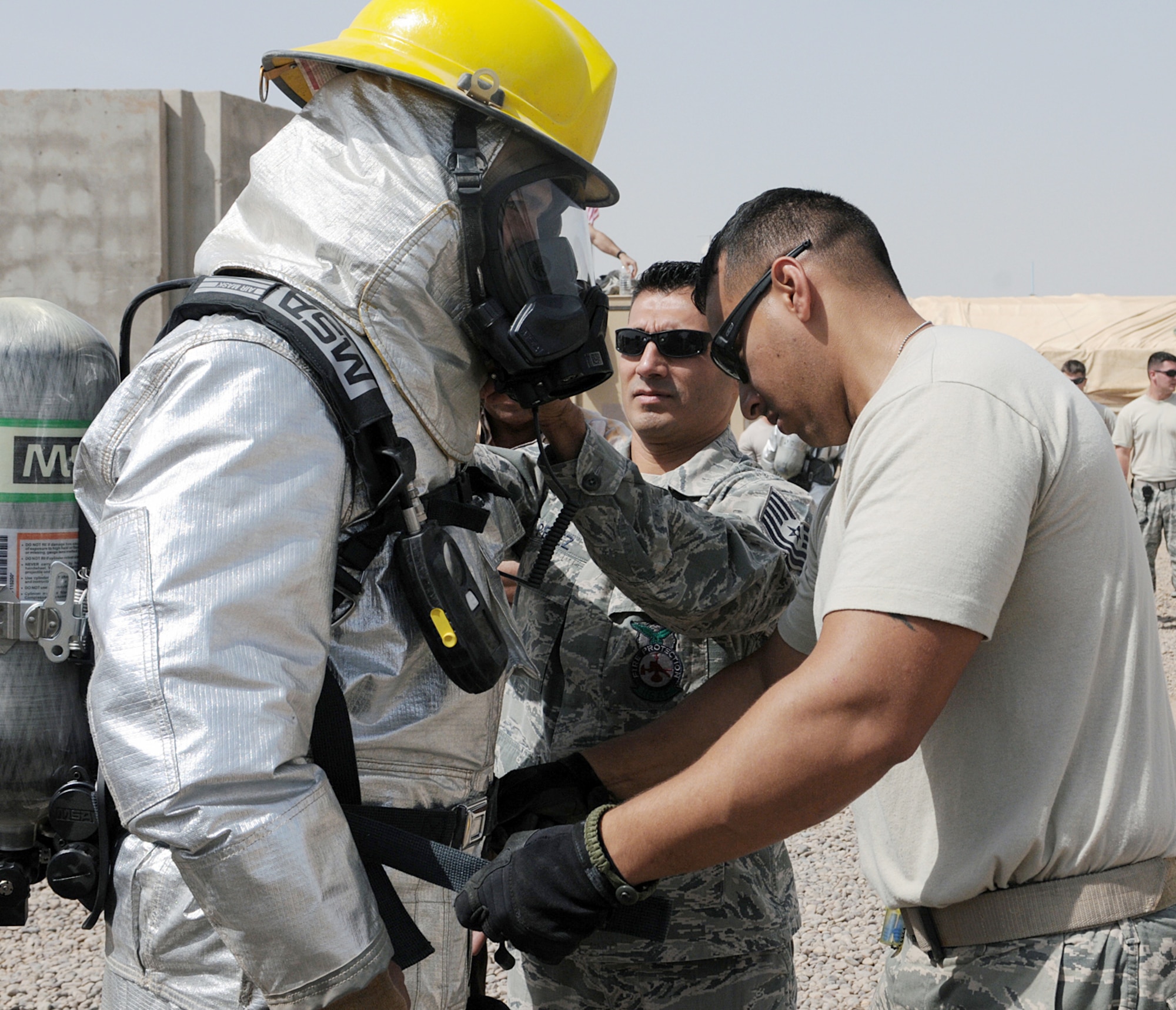 Staff Sgt. Stephen Sanabria (right) and Tech. Sgt. Stephen Perez help an Iraqi firefighter don his personal protective equipment prior to fighting a fire April 30, 2010, at Joint Base Balad, Iraq. Sergeant Sanabria is a firefighter with the 332nd Civil Engineer Squadron. Sergeant Perez is an assistant chief of fire prevention with the 332nd Civil Engineer Squadron. (U.S. Air Force photo by Master Sgt. Linda C. Miller)