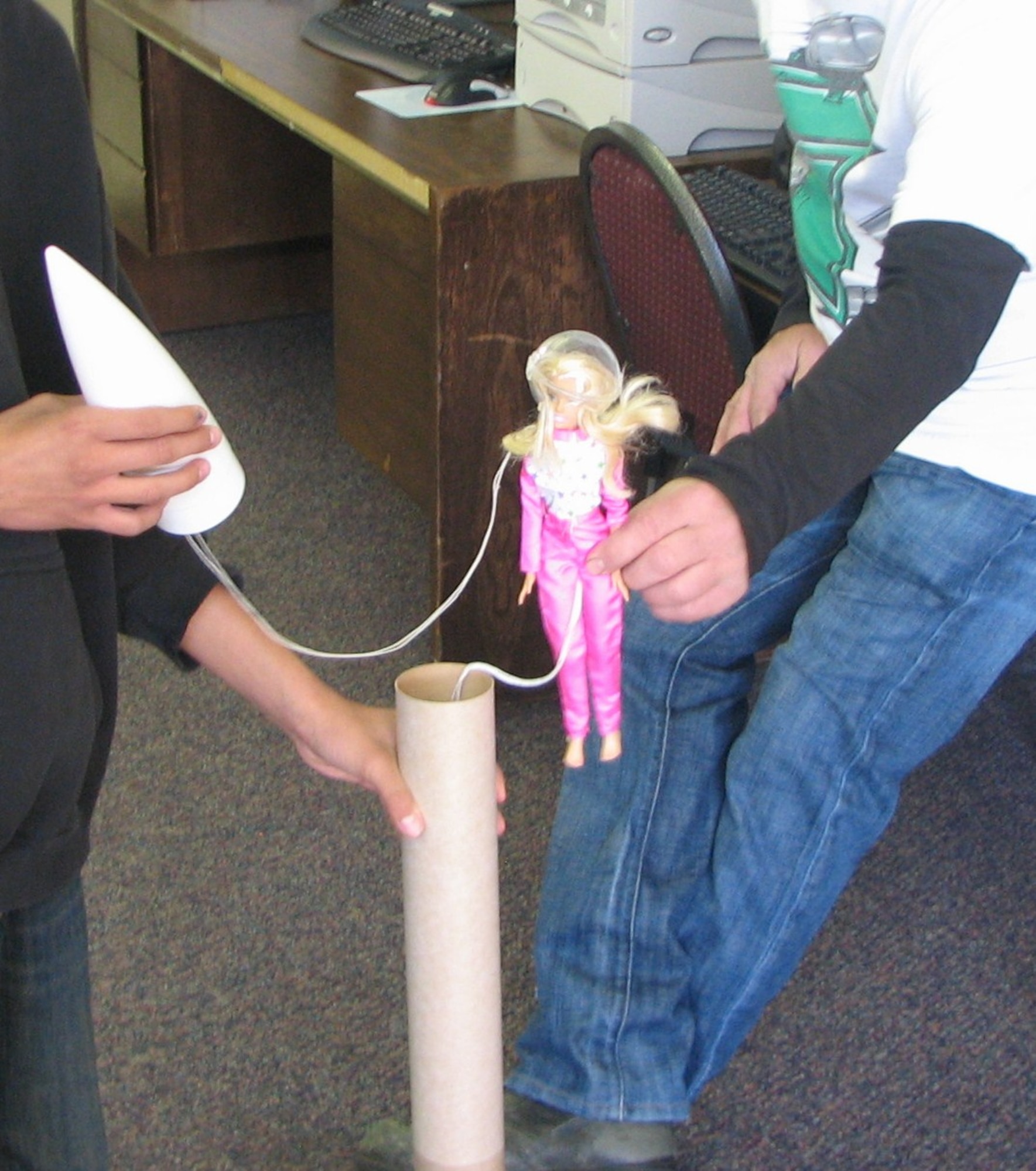 Rocket pilot Barbie, complete with a pink space suit, gets ready to board Samantha's rocket.  Barbie was to bail out of the rocket after the rocket deployed its parachute.  The rocket landed safely but Barbie had problems with her chute and lost her head when she hit the ground hard. Samantha launched her rocket April 27 and is now preparing for the "Eggstraordinary" Space Challenge June 7.  