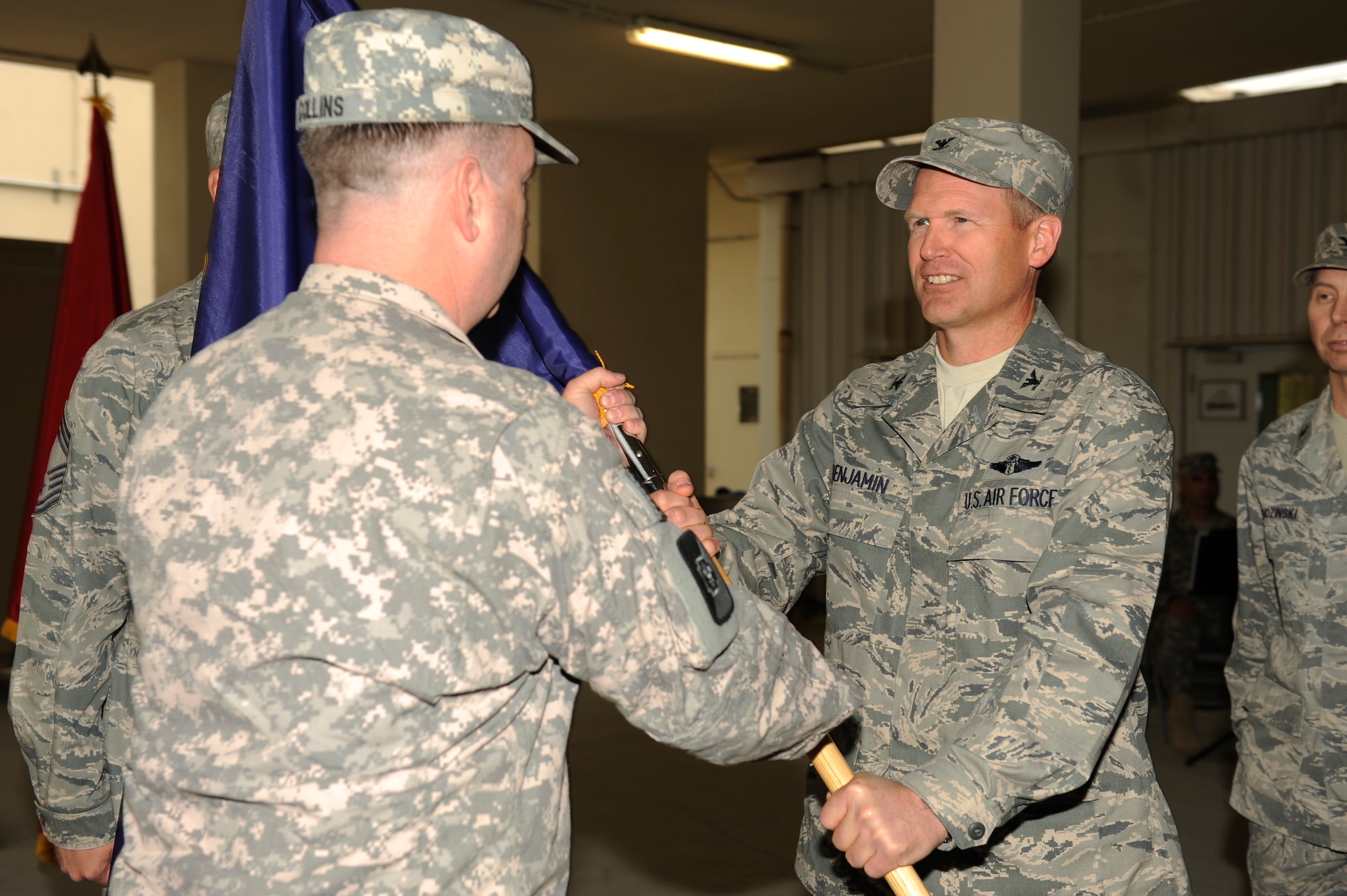 U.S. Army Col. John Collins, commander, Task Force 62nd Medical Brigade, gives the guidon to U.S. Air Force Col. (Dr.) Christian Benjamin, 455th Expeditionary Medical Group/ Task Force Medical East, during a change of command ceremony at Bagram Airfield, Afghanistan, May 4, 2010. (U.S. Air Force photo by/ Master Sgt. Jeromy K. Cross/released)