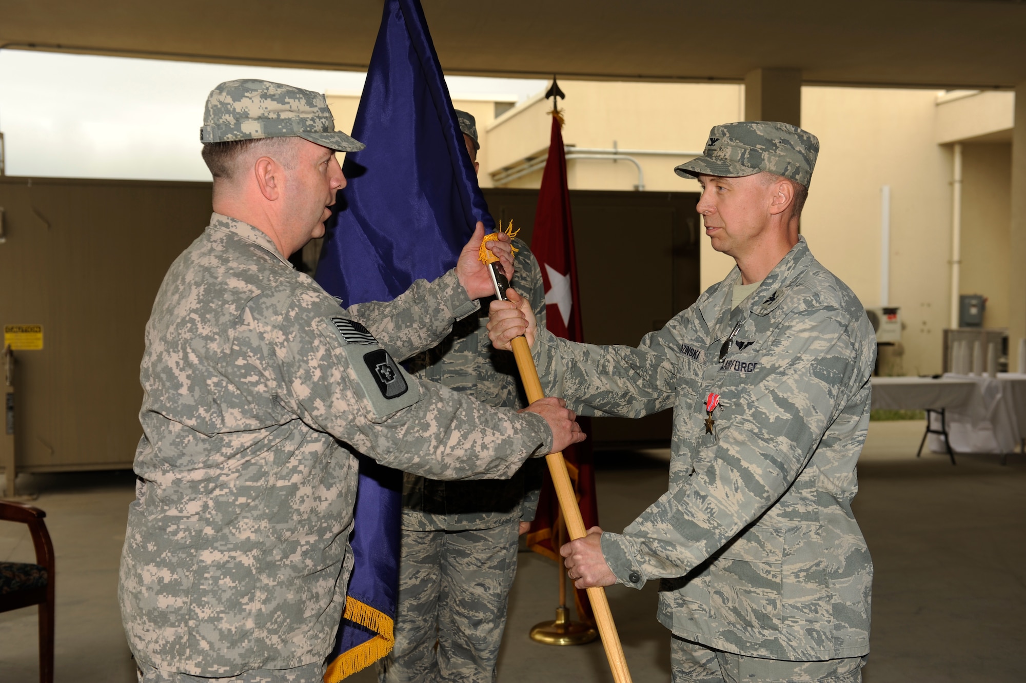 U.S. Army Col. John Collins, commander, Task Force 62nd Medical Brigade, accepts the guidon as U.S. Air Force Col. (Dr.) Joseph Chozinski, 455th Expeditionary Medical Group/ Task Force Medical East, relinquishes command during a change of command ceremony at Bagram Airfield, Afghanistan, May 4, 2010. (U.S. Air Force photo by/ Master Sgt. Jeromy K. Cross/released)