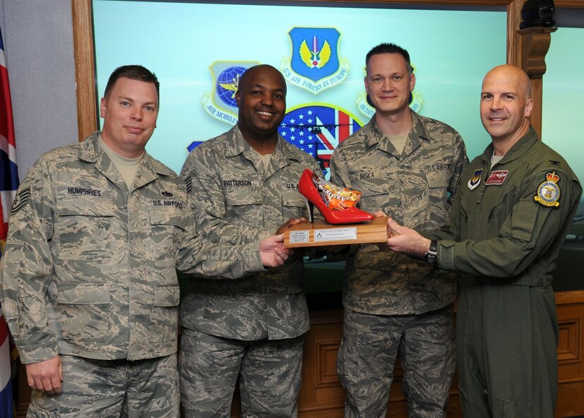 RAF MILDENHALL, England – Col. Chad Manske, 100th Air Refueling Wing Commander, presents Tech. Sergeants David Humphries, Jonas Patterson and Ivan Niska, 100th Aircraft Maintenance Squadron, with an award for being the winning team in the “Walk a Mile in Their Shoes Contest” May 5.  The contest pitted 12 10-man teams against each other in a month-long walking contest in support of Sexual Assault Awareness Month.  (U.S. Air Force photo/Staff Sgt. Jerry Fleshman)