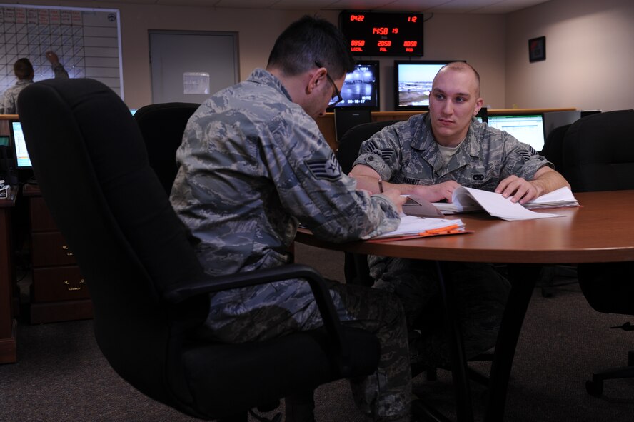 MINOT AIR FORCE BASE, N.D. -- Staff Sgt. Michael Kohut, 5th Logistics Readiness Squadron logistics planner, listens as Staff Sgt. Alan Solis call off chalk times during deployment tracking at here April 22.  The Individual Readiness Cell is the focal point for the base in supporting exercise, deployments and combat support. (U.S. Air Force photo by Tech. Sgt. Lee A. Osberry Jr.)