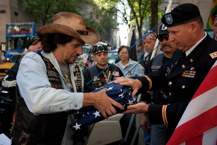 Army Lt. Col. Scott Wales, executive officer for Division of Strategic Command, Warrior Transition Command, passes a flag flown over the World Trade Center's construction site to Michael Garguilo, president of the military veteran motorcycle organization Rolling Thunder''s Staten Island chapter, May 5, 2010. Rolling Thunder members will bring the flag from New York City to Coloroado Springs, Co., for the 2010 Warrior Games.  The competition for wounded service members will take place May 10-14 at the US Olympic Training Center.