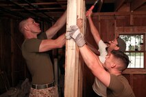 Sgt. Nathan Stark, a Union, Mo., native, and Lance Cpl. Andrew Mayer, a St. Louis native, both with Headquarters and Service Company, 3rd Battalion, 24th Marine Regiment, lend some strength by holding up a wall frame for Gerry Patton, the construction superintendent for Habitat for Humanity, Greater Boston, while reconstructing the ground floor for a house on Ashton Street in South Boston May 5, 2010.