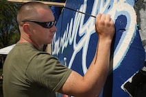 U. S. Marine Corps Lance Cpl. Pablo Morrison, Combat Reproduction Specialist, Marine Corps Base Quantico, Va., paints a Marine Corps themed mural at Hyde Park, Boston in support of Marine Week Boston, May 5, 2010. Marine Week Boston provides an opportunity to increase public awareness of the Marine Corps' value to our nation's defense and to preserve and mature the Corps' relationship with the American people.