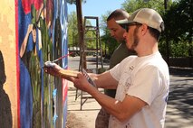 Gregg Bernstein, Assistant Director of the Mayor's Mural Crew (front) and U. S. Marine Corps Cpl. Kristofer Atkinson, 4th Marine Corps Recruiting District, Recruiting Station New Cumberland, Pa., paint a Marine Corps themed mural at Hyde Park, Boston in support of Marine Week Boston, May 5, 2010. Marine Week Boston provides an opportunity to increase public awareness of the Marine Corps' value to our nation's defense and to preserve and mature the Corps' relationship with the American people.