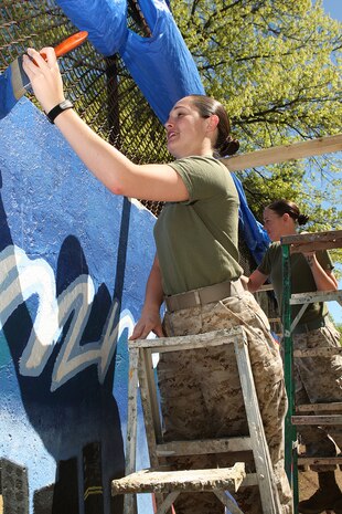 U. S. Marine Corps Cpl. Erin Carpenter, Marine Forces Reserve, Mobilization Command, New Orleans, La., paints a Marine Corps themed mural at Hyde Park, Boston in support of Marine Week Boston, May 5, 2010. Marine Week Boston provides an opportunity to increase public awareness of the Marine Corps' value to our nation's defense and to preserve and mature the Corps' relationship with the American people.