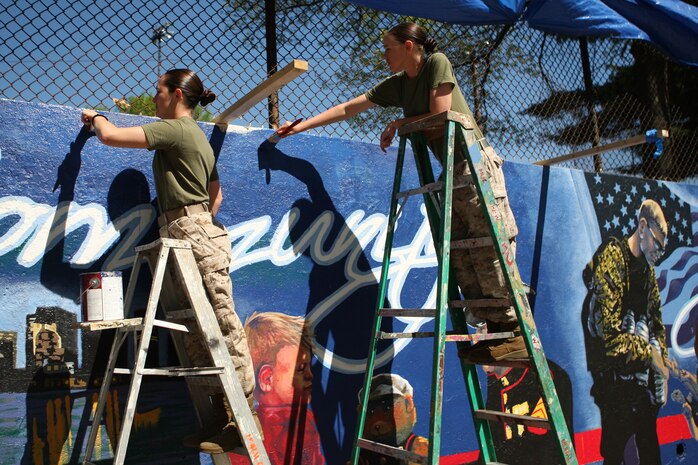 U. S. Marine Corps Cpl. Erin Carpenter, Marine Forces Reserve (MFR), Mobilization Command (left), and Sgt. Tiffany Benson, MFR G-4, New Orleans, La., paint a Marine Corps themed mural at Hyde Park, Boston in support of Marine Week Boston, May 5, 2010. Marine Week Boston provides an opportunity to increase public awareness of the Marine Corps' value to our nation's defense and to preserve and mature the Corps' relationship with the American people.