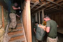 Sgt. Zachary Rigg, a St. Louis native, sweeps the stairs while Lance Cpl. James Reese, a St. Louis native, and Sgt. Joshua Paxson, an Affton, Mo., native, clear out trash from a house in Boston May 5, 2010. The Marines, all with Headquarters and Service Company, 3rd Battalion, 24th Marine Regiment, were helping construct a house as an outreach program during Marine Week Boston.