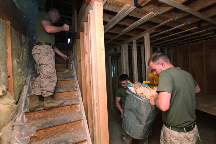 Sgt. Zachary Rigg, a St. Louis native, sweeps the stairs while Lance Cpl. James Reese, a St. Louis native, and Sgt. Joshua Paxson, an Affton, Mo., native, clear out trash from a house in Boston May 5, 2010. The Marines, all with Headquarters and Service Company, 3rd Battalion, 24th Marine Regiment, were helping construct a house as an outreach program during Marine Week Boston.