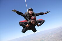 SkyHawks Tandem Master Travis Hegland jumps with Staff Sgt. Keith Lawson, 4th Combat Camera Squadron. The cord above their head is for a drogue chute which ensures the jumpers' speed does not exceed 120 mph. (Canadian Forces SkyHawks Parachute Team photo)