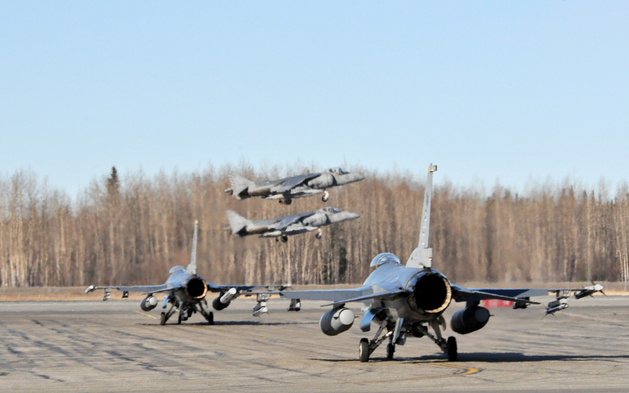 Two Marine AV-8B Harriers take off as two F-16 Fighting Falcons await their turn during Red Flag-Alaska at Eielson Air Force Base, Alaska, April 21, 2010. Harriers are from VMA 211 at Marine Corps Air Station in Yuma, Ariz. (U.S. Air Force photo/Capt. Shannon Collins)
