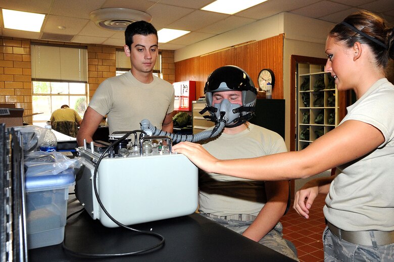 OFFUTT AIR FORCE BASE, Neb. -- Airman 1st Class Rebecca Wheeler, an aircrew flight equipment technician with the 55th Operations Support Squadron, uses the simulated Scot Tester to perform a fit test with a HGU-55P (flyer's helmet) on Airman Devin Williams, also an aircrew flight equipment technician with the 55th OSS, while Airman 1st Class Steven Cunningham, 55th OSS, looks on. The Scot Tester pre-flight procedures insure equipment is tested for normal and high altitudes before aircrews here deploy. U.S. Air Force Photo by Kendra Williams
