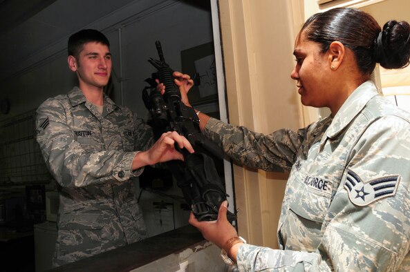 U.S. Air Force Senior Airman Alex Houston, 586th Air Expeditionary Group armorer, accepts a cleared weapon from Senior Airman Jimarie Candelario, also of the 586th AEG, at the armory of an undisclosed location in Southwest Asia May 5, 2010. (U.S. Air Force photo by Staff Sgt. Lakisha A. Croley/Released)