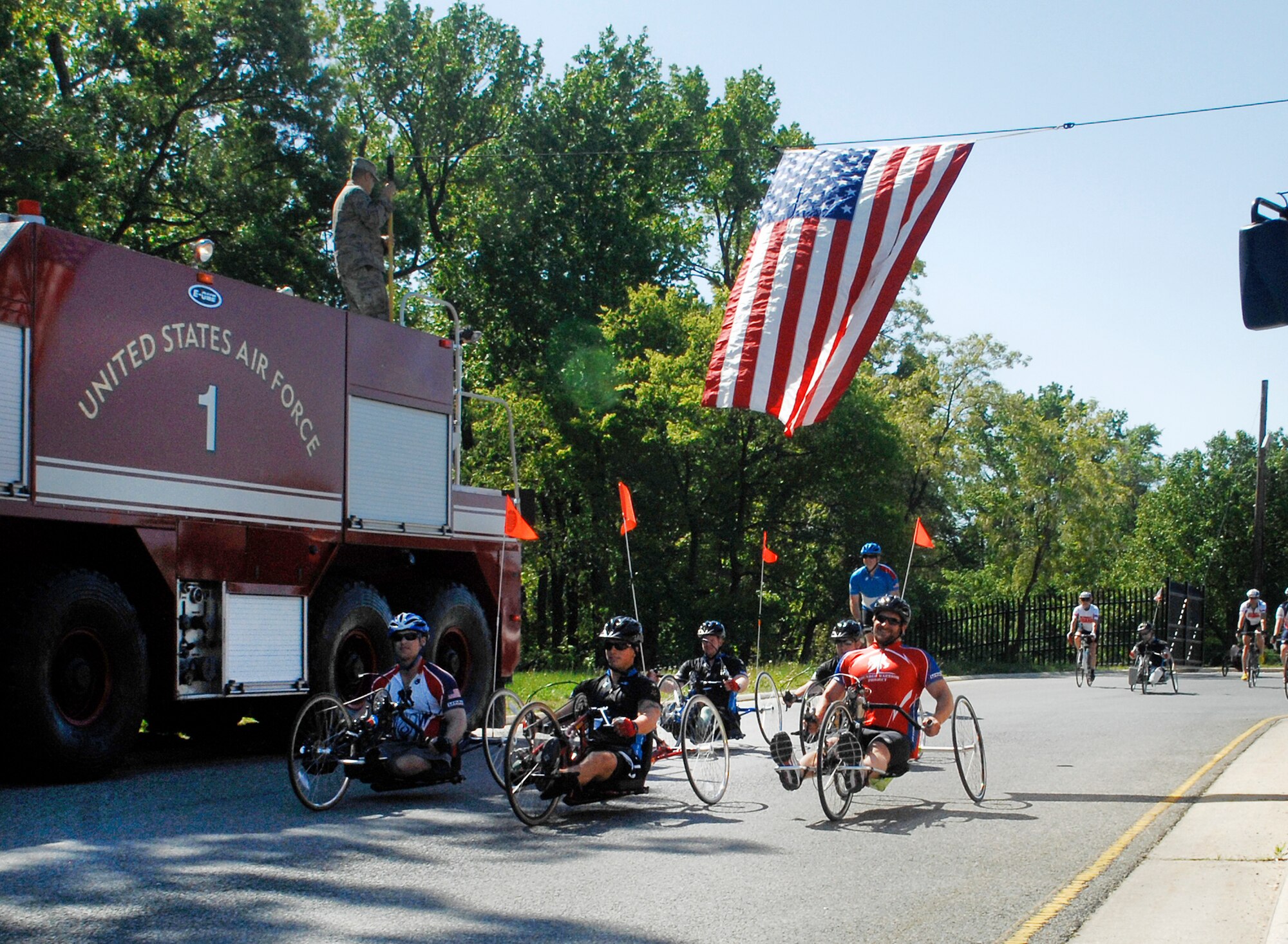 The first wave of wounded warrior cyclists roll past a 316th Civil Engineer Squadron fire truck on their way out of Joint Base Andrews’ North Gate to cheers of encouragement from on-lookers during the 4th Annual Wounded Warrior Project’s Soldier Ride, which started April 28, 2010, at the White House and ended Saturday in Annapolis, Md. (U.S. Air Force photo by Senior Airman Melissa Brownstein)