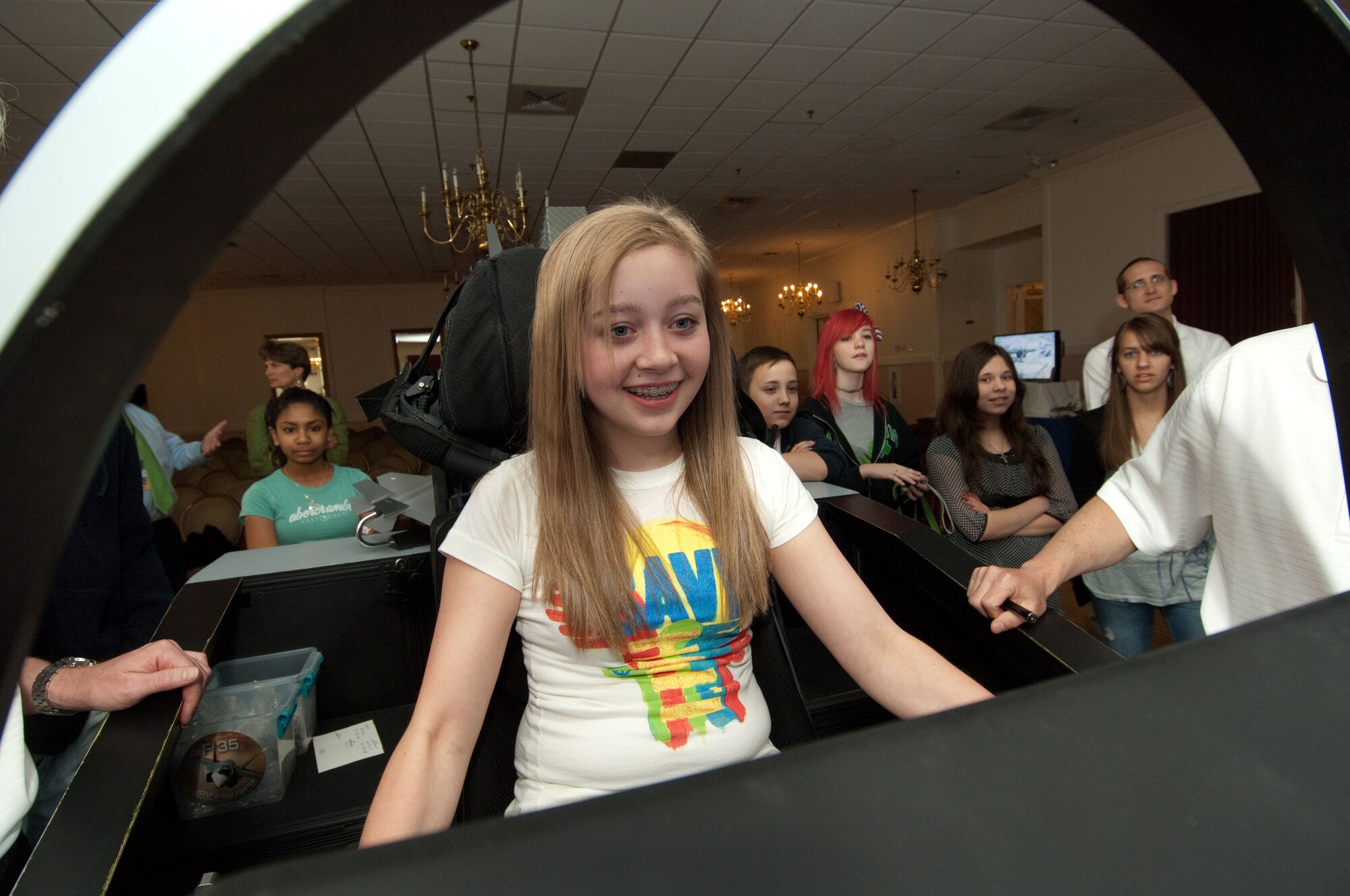 HANSCOM AIR FORCE BASE, Mass. – Kimber Knapp tries flying an F-35 over Nellis Air Force Base while her classmates from Hanscom Middle School watch. Representatives from Lockheed Martin brought an F-35 simulator to the Minuteman Club from April 27-29. (U.S. Air Force photo by Rick Berry)