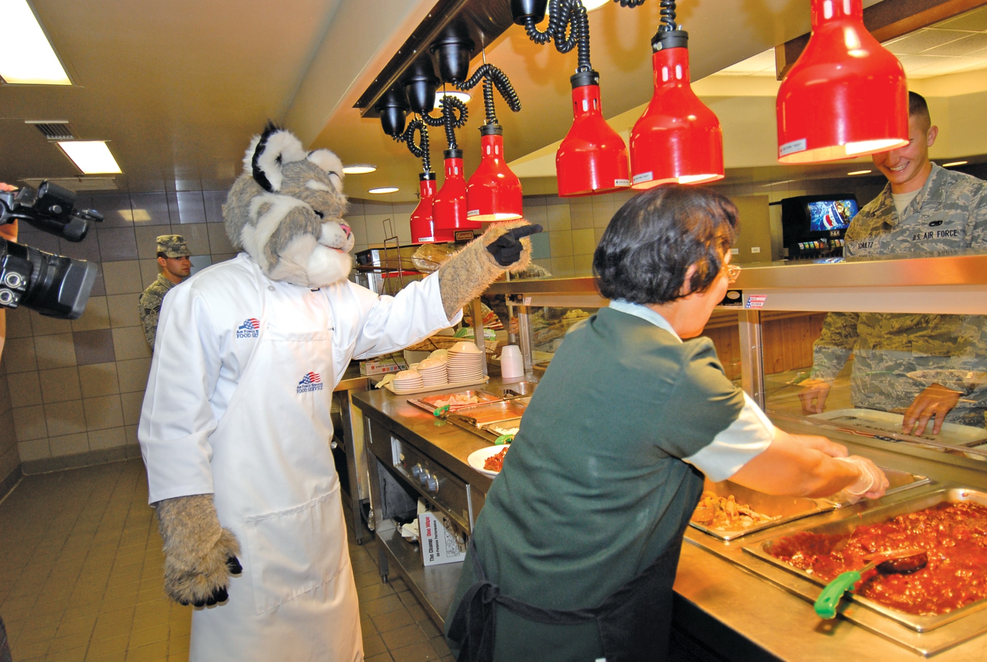 Arizona Diamondbacks mascot, Baxter the Bobcat, serves food at the Ray V. Hensman Dining Facility during his visit to Luke April 27.  (U.S. Air Force photo by Airman 1st Class Ronifel Yasay)