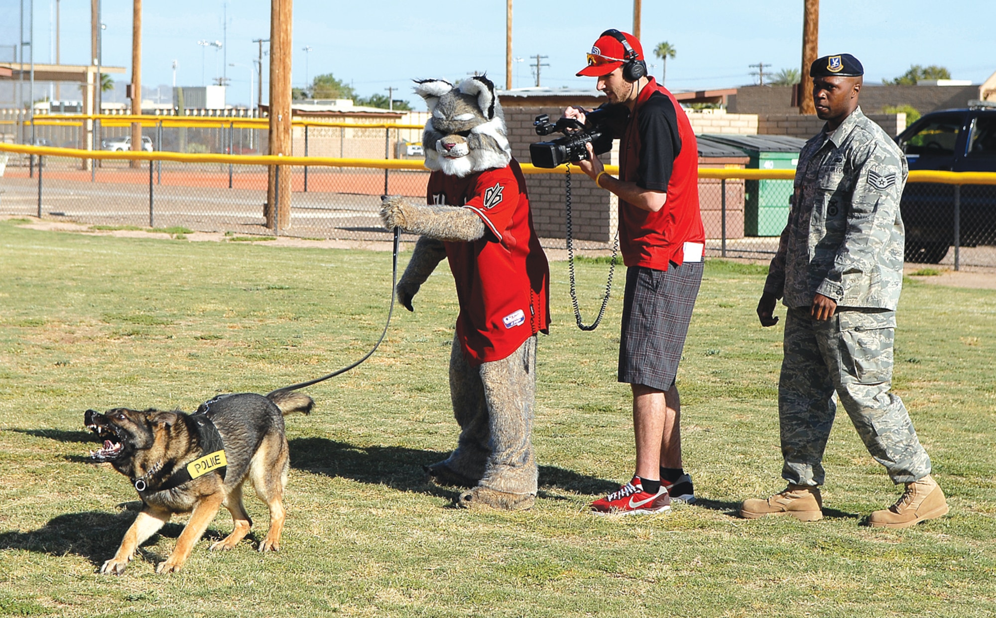 Baxter the Arizona Diamondbacks mascot holds onto the leash of Mirko, 56th Security Forces Squadron Military Working Dog, alongside of Staff Sgt. Charles Wilder, 56 SFS MWD trainer, during his visit to Luke to capture some video Apr. 27. The footage from the day's events will be showcased July 4 during the All-American Weekend and Military Appreciation Day when the Diamondbacks play the Los Angeles Dodgers.  (U.S. Air Force photo by Airman 1st Class Ronifel Yasay)