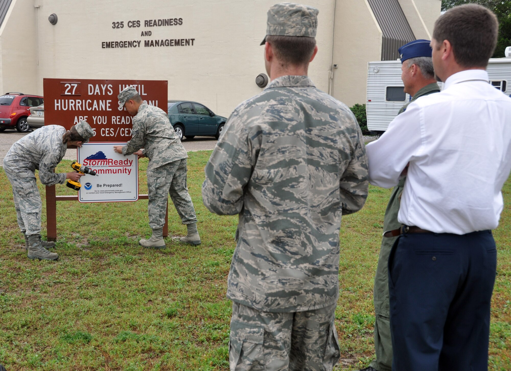 Airmen from the 325th Civil Engineer Readiness and Emergency Management Flight hang a Storm Ready Community sign in front of their building to recognize they are prepared for the upcoming hurricane season. (U.S. Air Force photo by Airman 1st Class Rachelle Elsea)