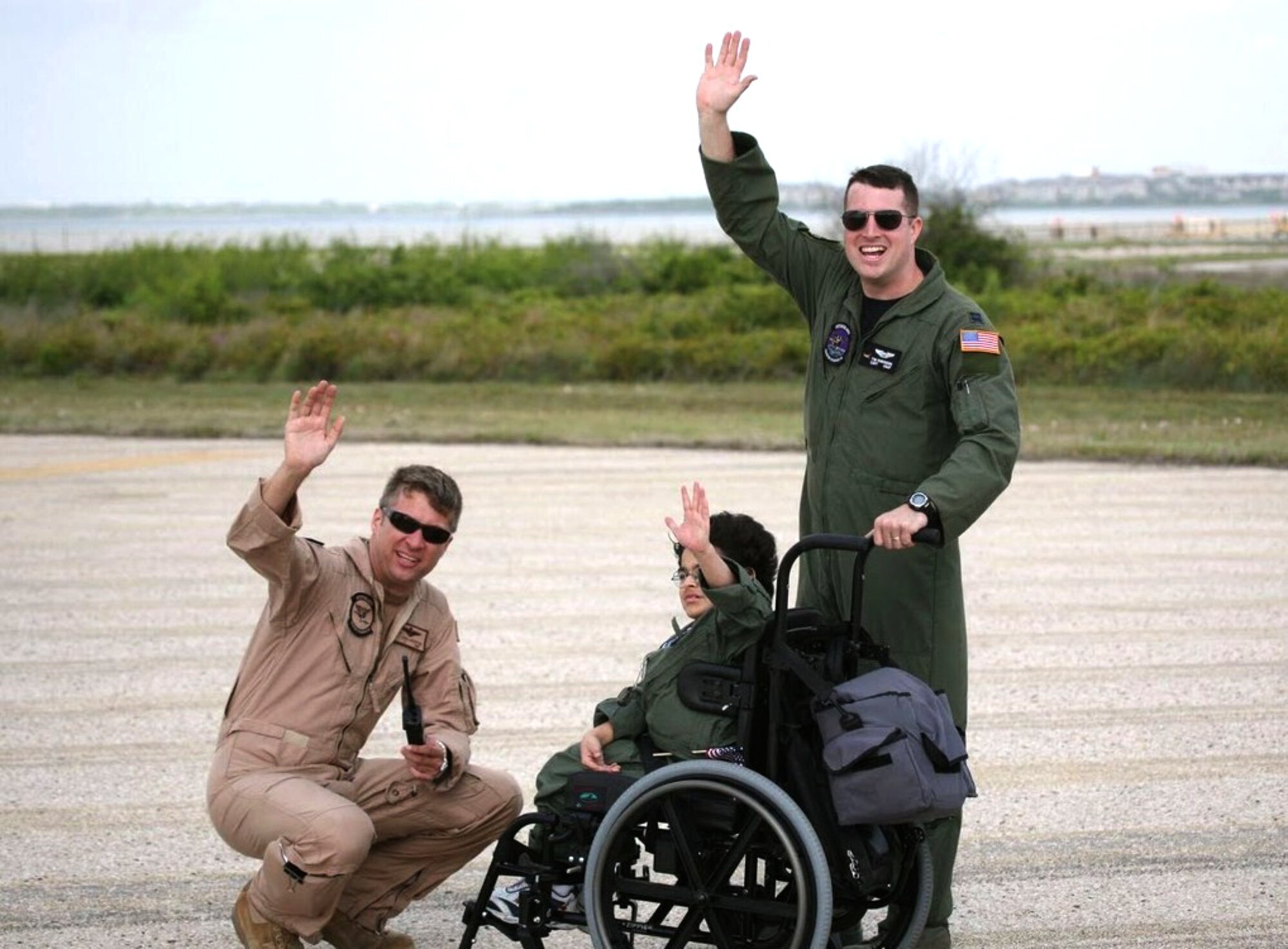 Navy Lt. Josh Lostetter, Pilot for a Day Eric Davis and Capt. Tim Robinson wave at a passing B-52 Stratofortress as it flies over the runway May 1, 2010, at Naval Air Station Corpus Christi, Texas. When scheduling allows, 2nd Bomb Wing members use the missions to practice off-station low approaches while providing support for the Pilot-For-A-Day program. (U.S. Coast Guard photo/Charles Dekle)