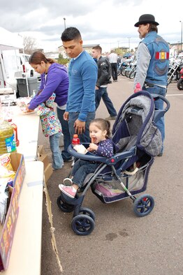 Senior Airman Marvin Reyes, 341st Civil Engineer Squadron, watches as his daughter Alana, 2, takes a bite of a hot dog. The free food at the annual Rolling Thunder event was donated by the Top 3, first sergeants and chiefs. Members of the 341st CES "Dirt Boyz" did the cooking. (U.S. Air Force photo/Valerie Mullett)