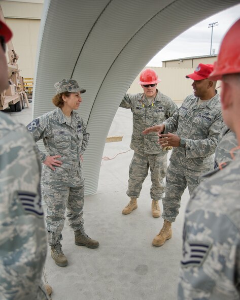 Chief Master Sgt. Cari Kent, 341st Missile Wing command chief, listens as Chief Master Sgt. Brian Richardson explains a construction procedure while Staff Sgt. Joseph Hensley and others listen in. (U.S. Air Force photo/Beau Wade)