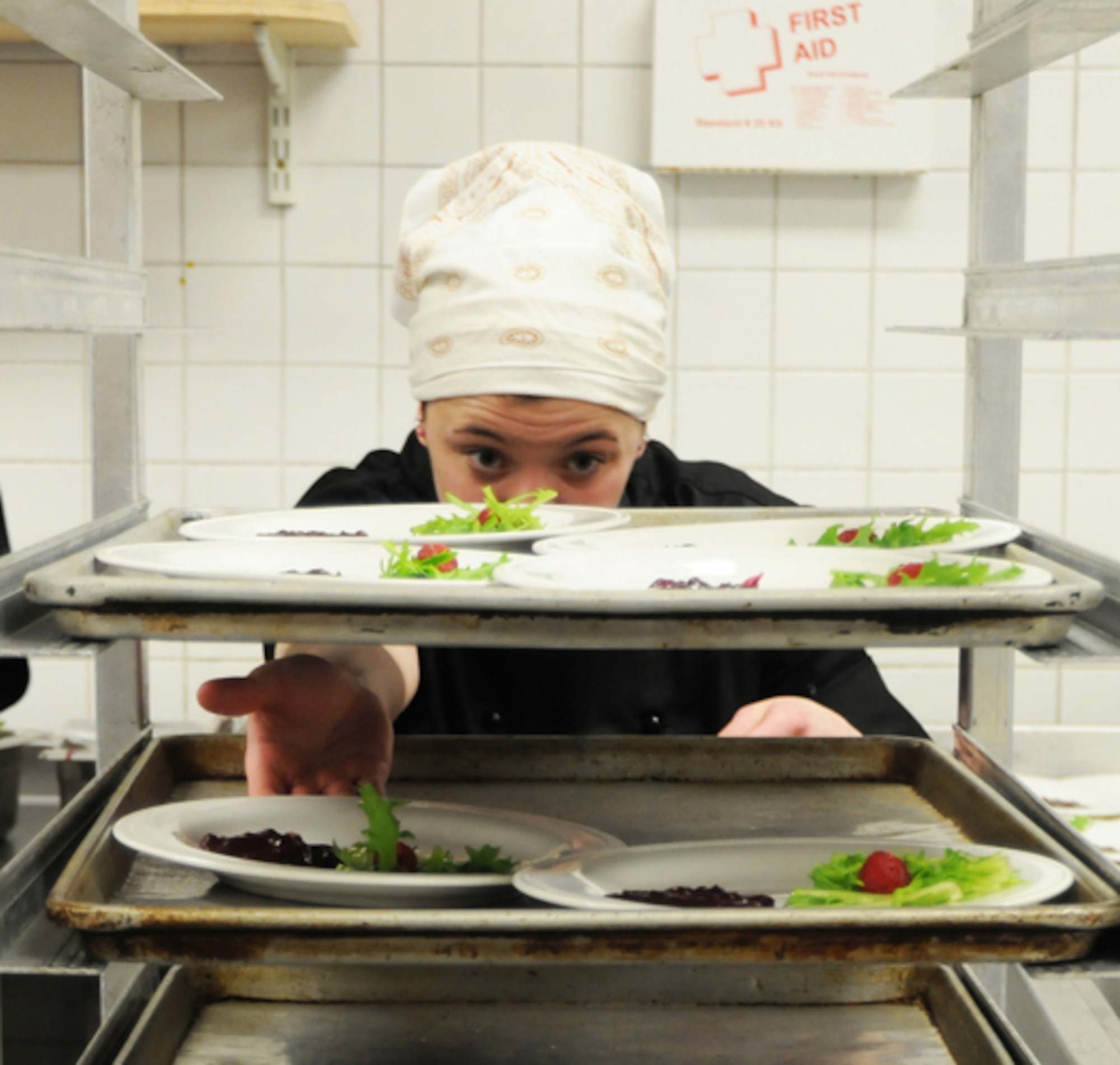 Nichole Hoover, Liberty Club red team chef, prepares garnished plates for main entrees for the Hell’s kitchen cook-off at the Liberty Club at RAF Lakenheath, England,  April 24. Hoover was a member of the civilian chef team who competed against the military chefs. The military chefs made up for last year’s defeat with a win over the civilians. (U.S. Air Force photo/Airman 1st Class Lausanne Morgan)