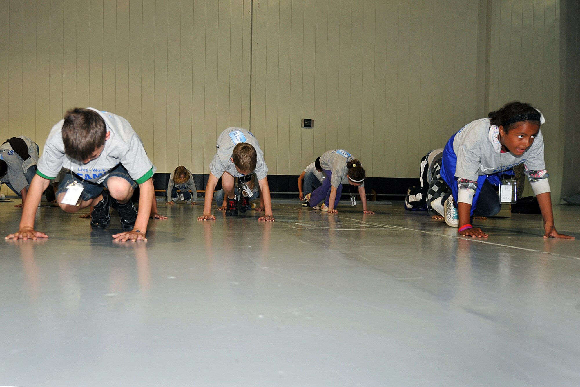 OFFUTT AIR FORCE BASE, Neb. -- Many children of various ages from various schools learn to bear-crawl during the Junior PDF Line event at the Offutt Field House May 7. More than 260 military children attended the event to gain a better understanding of what their parents experience when they deploy. U.S. Air Force Photo by Charles Haymond